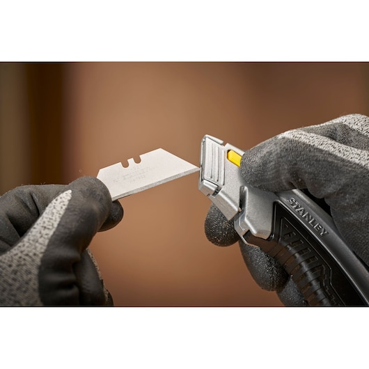 STANLEY 0-10-788 utility knife with blade being inserted, close-up, black and gray gloves.
