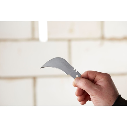 STANLEY 0-11-980 curved utility knife blade held in hand, silver, photography close-up.