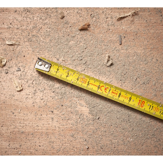 STANLEY 0-30-687 yellow tape measure on dusty brown surface, close-up angle.