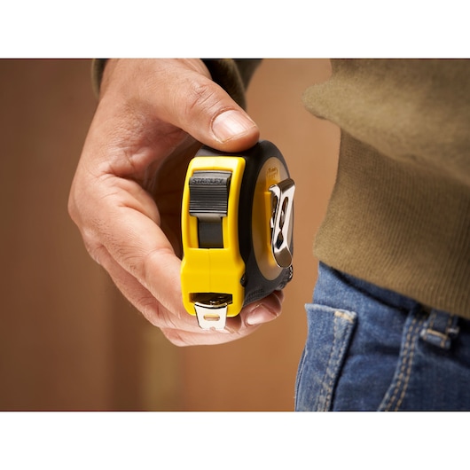 STANLEY 0-30-697 tape measure with yellow and black casing held near jeans pocket.