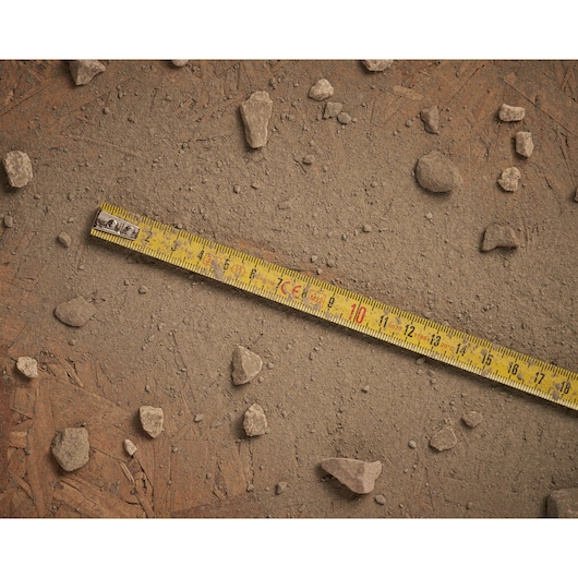 Stanley 0-32-125 yellow measuring tape on dusty ground with scattered rocks, flat angle photography.