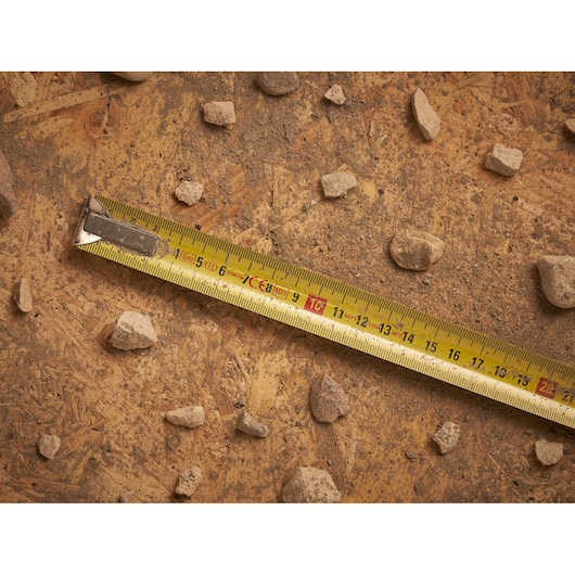 STANLEY 0-33-195 tape measure on rough surface with scattered rocks, photography product.