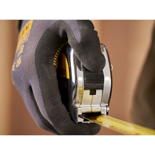 STANLEY 0-33-195 tape measure held in gloved hand with yellow measuring tape extended.