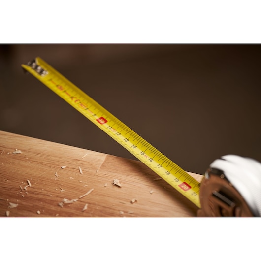 Photo of STANLEY 0-33-522 tape measure extended over wood surface with sawdust, product close-up.