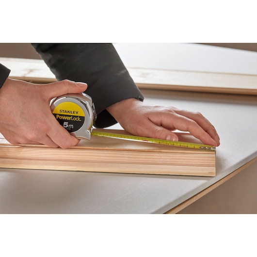 STANLEY 0-33-552 tape measure used to measure wood on tabletop, close-up photography.