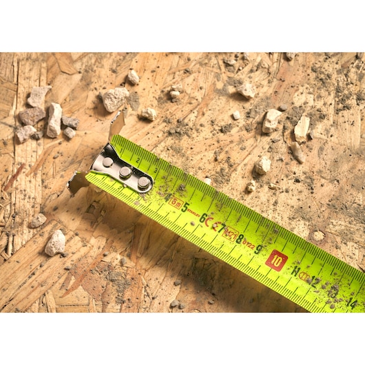 STANLEY 0-33-887 tape measure on plywood with debris, close-up angle.