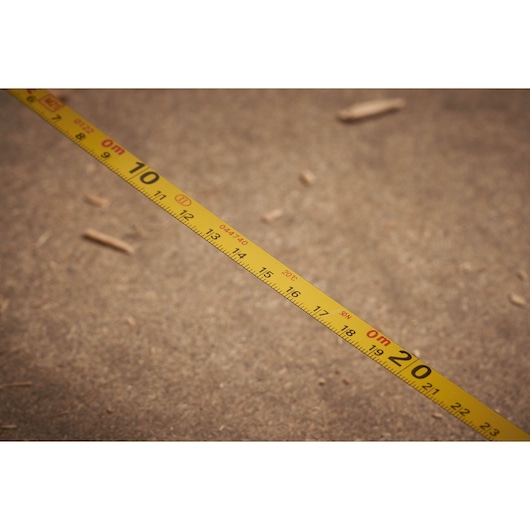 STANLEY 0-34-102 yellow measuring tape stretched on rough surface, showing clear metric markings.