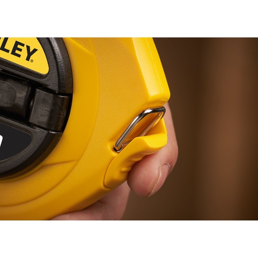 STANLEY 0-34-105 yellow measuring tape case with metal hook, close-up detail in hand.