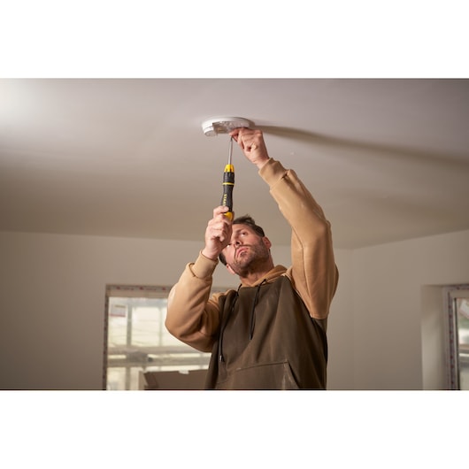 Photo of STANLEY 0-68-010 screwdriver used to install a smoke detector on a white ceiling.
