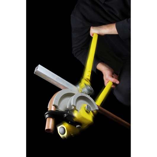 STANLEY 0-70-452 pipe bender with yellow handles shown bending a copper pipe, photographed with user action.