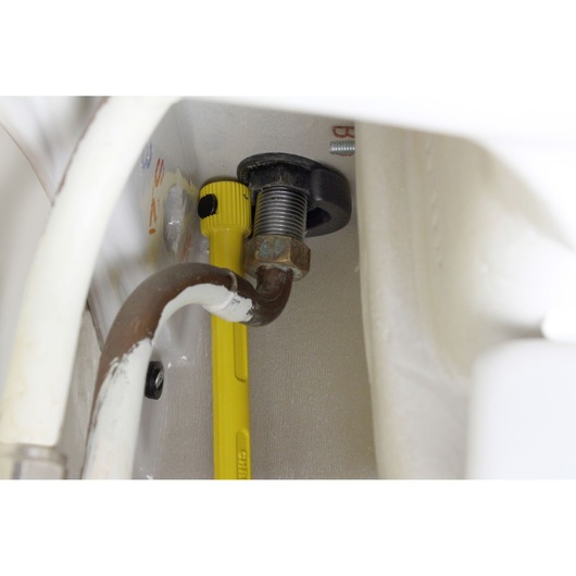 STANLEY 0-70-453 adjustable wrench on plumbing nut, close-up inside cabinet.