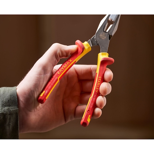 STANLEY 0-84-001 insulated pliers with red and yellow handles held in hand, close-up photo.