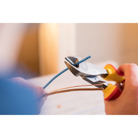Photo of STANLEY 0-84-004 wire cutter cutting blue wire, close-up of tool with yellow and red handles.