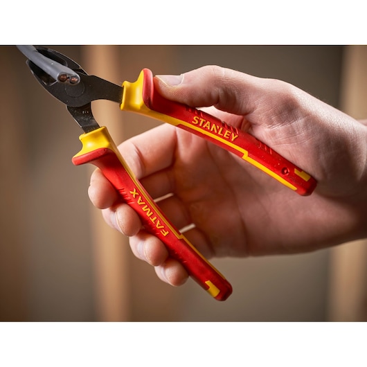 Stanley 0-84-009 pliers with FATMAX red and yellow handles, close-up held cutting electrical wire.