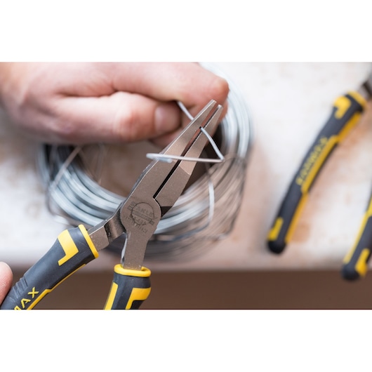 STANLEY 0-84-495 pliers with black and yellow handle, gripping metal wire close-up.