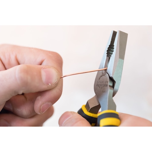 Stanley 0-89-866 pliers holding a copper wire, close-up view, black and yellow handle.