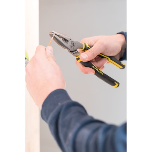 STANLEY 0-89-868 pliers being used to cut wire, close-up of black and yellow tool in hand.