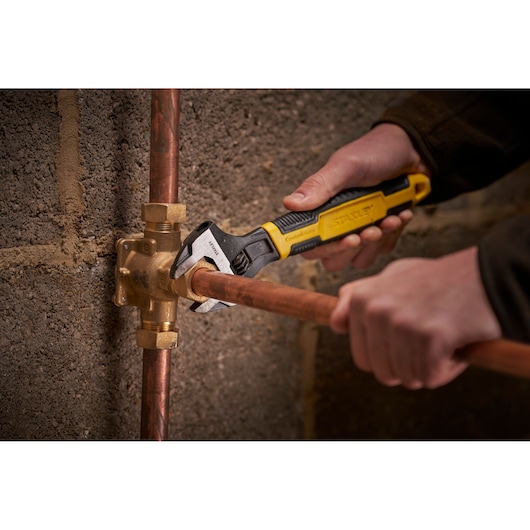 STANLEY 0-90-949 adjustable wrench used on copper pipe fitting, close-up photography.