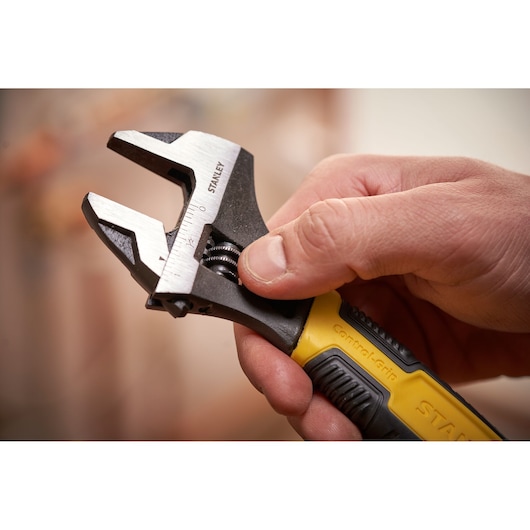 STANLEY 0-90-949 adjustable wrench with yellow and black grip held in hand, close-up photography.