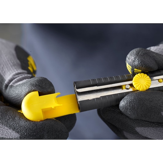 STANLEY 1-10-409 utility knife in black and yellow held by gloved hands, close-up angle.