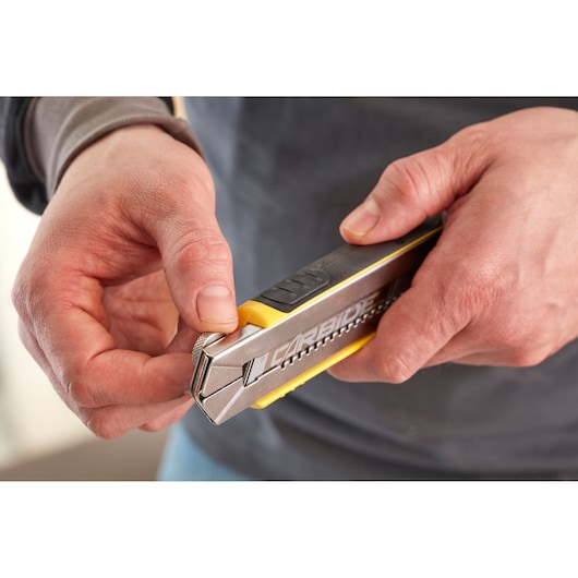 Photo of hands holding a STANLEY 1-10-481 utility knife with carbide blade, close-up view.