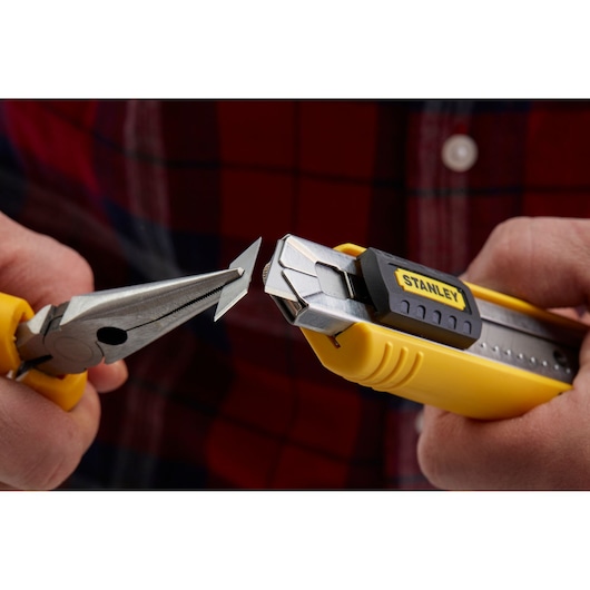 STANLEY 1-10-481 utility knife with yellow handle, blade being changed with pliers, close-up view.