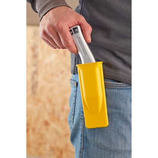 STANLEY 1-10-550 utility knife in yellow holster clipped to jeans, close-up side view.