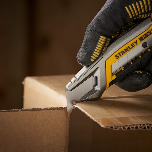 Stanley 1-11-301 utility knife cutting cardboard, close-up, photography of product in use.