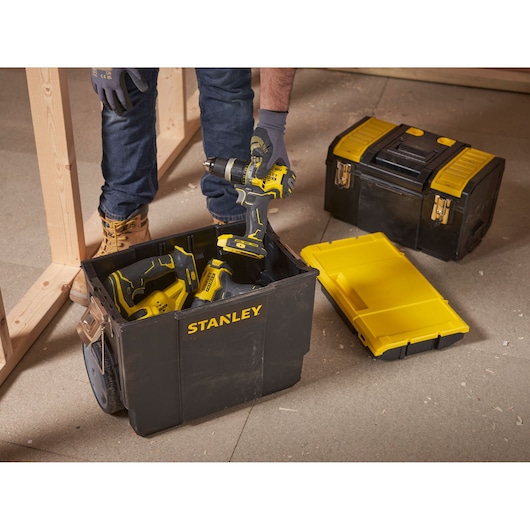 Photo of STANLEY 1-70-326 black and yellow toolbox with open lid, tools inside, on a construction site floor.