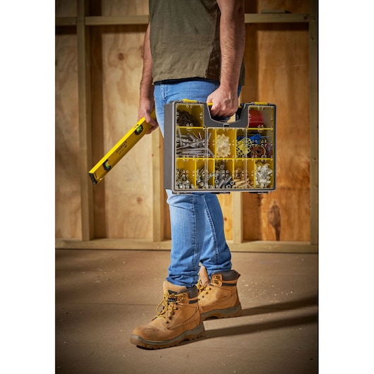 Photo of STANLEY 1-92-749 storage organizer with yellow compartments, carried by a person on a construction site.