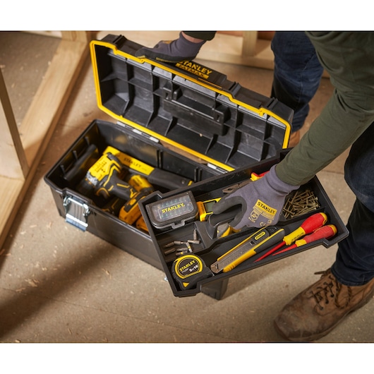STANLEY 1-94-749 toolbox with assorted hand tools and accessories in workshop setting, top angle.
