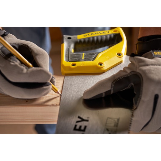 STANLEY 2-15-599 saw in use, gloved hands measuring and marking wood, close-up view.