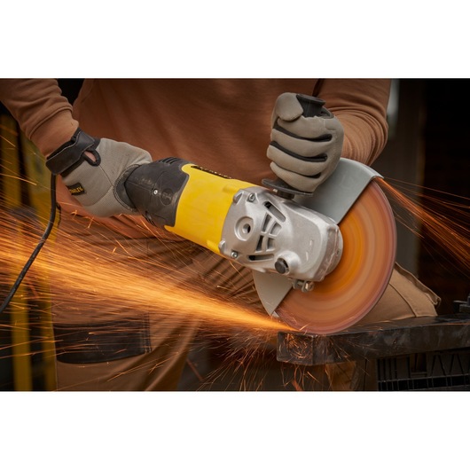 STANLEY FMEG232 angle grinder in use cutting metal, yellow and black body, sparks flying.