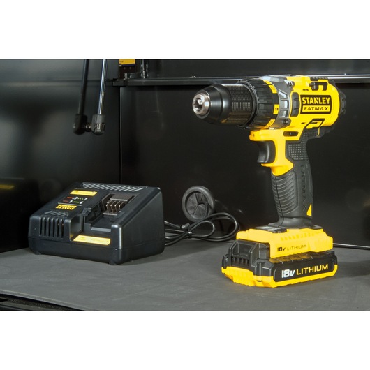 STANLEY FMHT0-74028 yellow cordless drill with 18V lithium battery and charger, side angle photo.