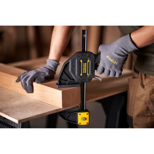 Stanley FMHT0-83238 photography of a one-handed clamp securing wood on a workbench.