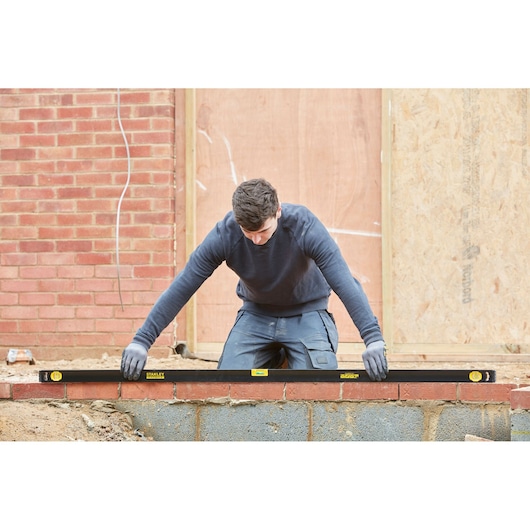 STANLEY FMHT42561-1 spirit level used by builder on brick wall construction site.