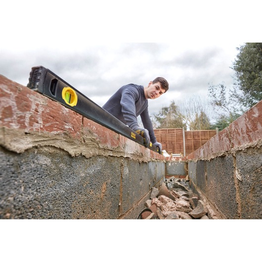 STANLEY FMHT42562-1 spirit level in use on brick wall, construction setting, angled view