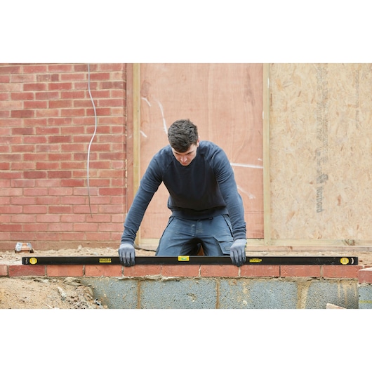 Photo of STANLEY FMHT42562-1 spirit level used on a brick wall at a construction site.