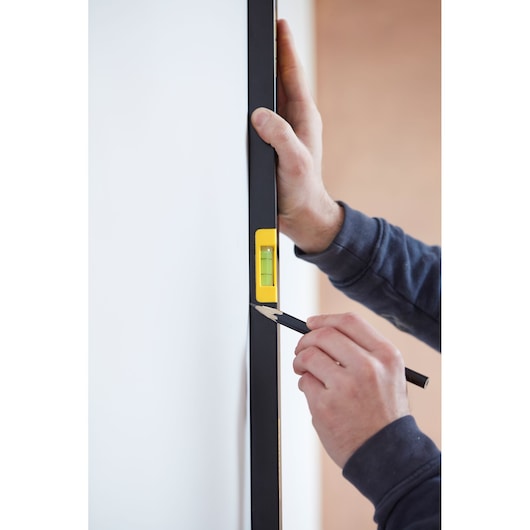 STANLEY FMHT42562-1 spirit level used against a white wall, close-up photography of marking with pencil.