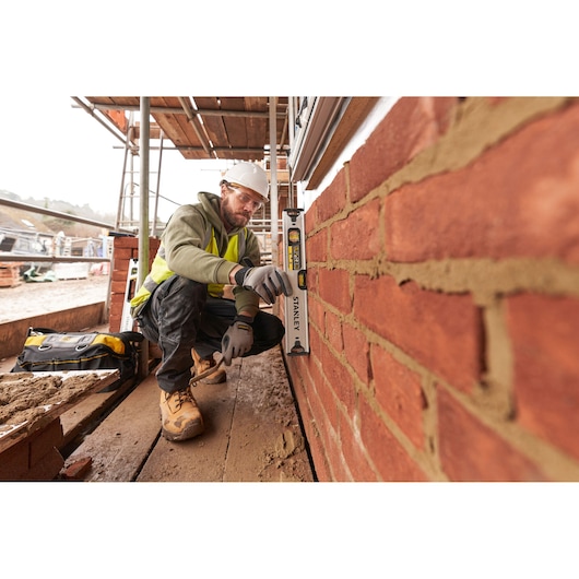Photo of a worker using a STANLEY FMHT43671-1 spirit level on a brick wall at a construction site.