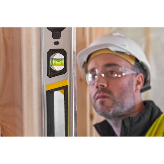 Stanley FMHT43675-1 spirit level close-up, vertical position, showing vial and yellow accent.
