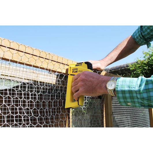 STANLEY FMHT6-70411 staple gun attaching wire mesh to wood frame outdoors.