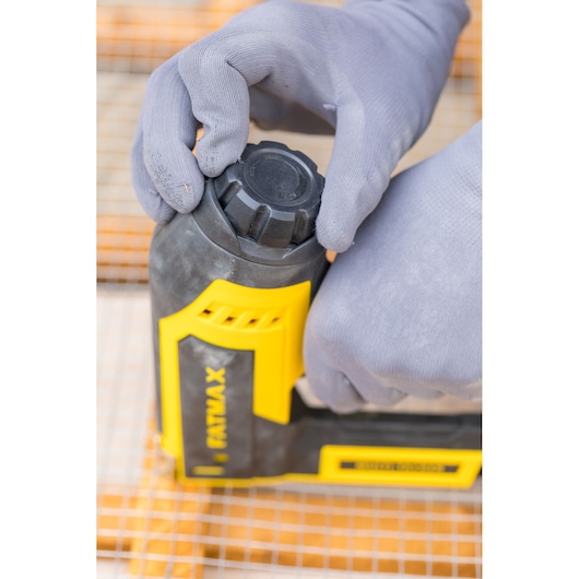 STANLEY FMHT6-75934 close-up photo of a person adjusting a yellow and black hand tool with gloved hands.
