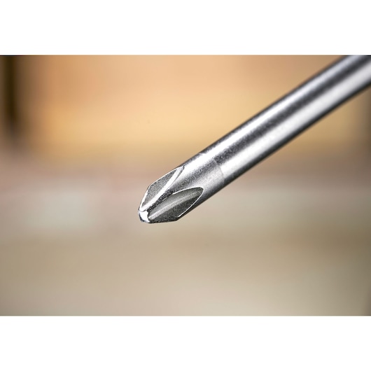 Close-up of a metal Phillips screwdriver tip with a blurred background.