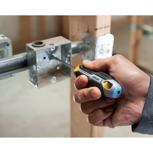 Hand using Stanley screwdriver to fasten screw in metal electrical box during installation.