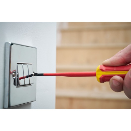Insulated screwdriver used to tighten a screw on a light switch.