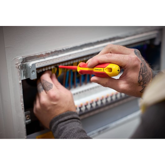 Person uses a STANLEY insulated screwdriver to work on electrical wiring in a panel.