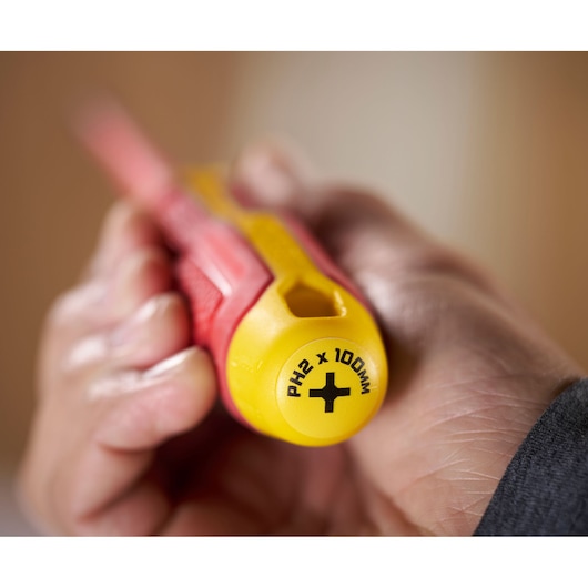 Close-up of a hand holding a STANLEY insulated Phillips screwdriver, PH2 x 100mm marked on handle end.