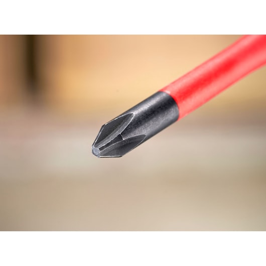 Close-up of a red-handled Phillips screwdriver tip against a blurred background.