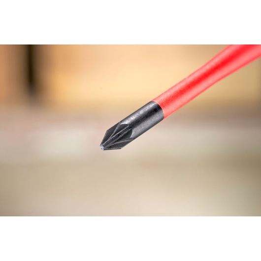 Close-up of a red-handled Phillips screwdriver tip against a blurred background.